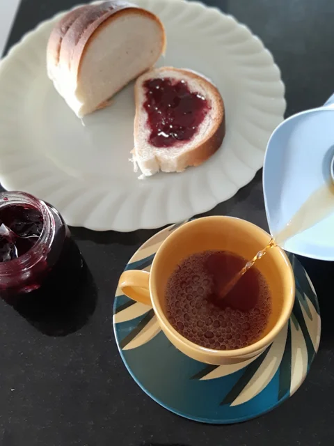Mesa de café da manhã com pão feito no forno à lenha, geleia e café feito na hora, uma maneira muito gostosa de começar o dia.